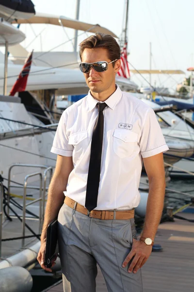 Красивий чоловік, серйозний капітан у білій сорочці біля яхти, дивлячись — стокове фото