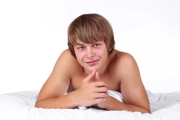 Porträtt av ung vacker man i vit säng — Stockfoto