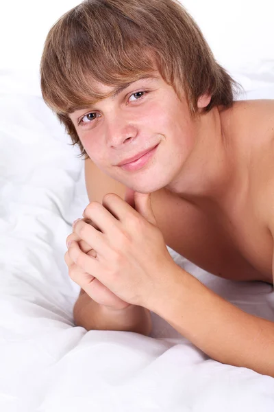 Молодой сексуальный мужчина лежит на белой кровати — стоковое фото