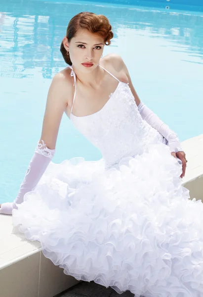 Hermosa novia posando cerca de la piscina en el día de su boda —  Fotos de Stock