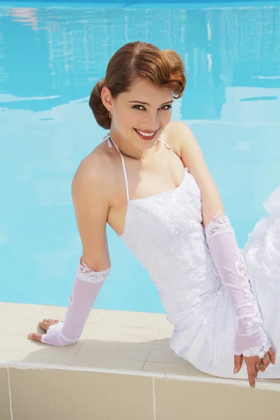 Beautiful woman in white dress near open-air swimming pool — Stock Photo, Image