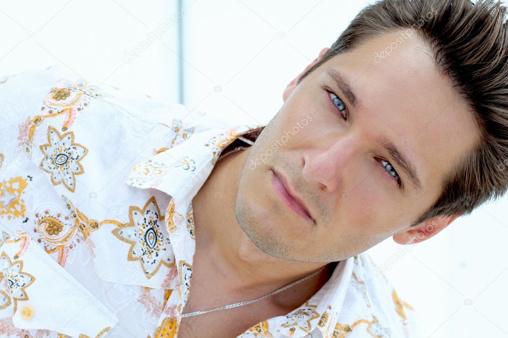 Portrait of handsome man with blue eyes on the beach, white yacht
