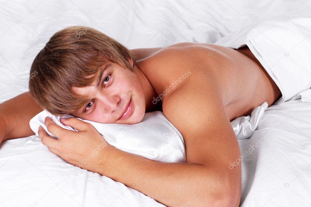 Smiling resting man on pillow in white bed