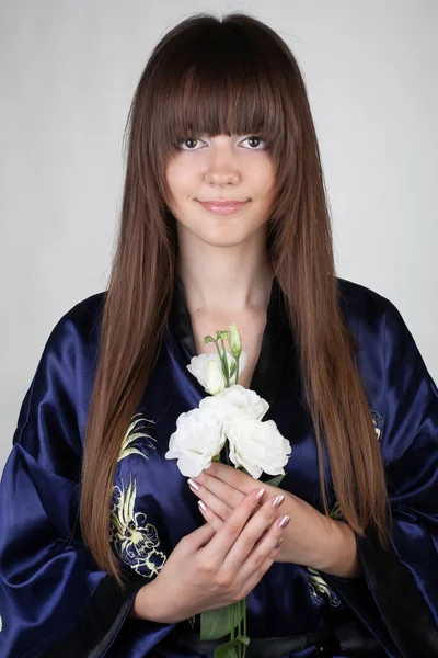 Portrét krásné orientální dívky s květinami v ruce — Stock fotografie