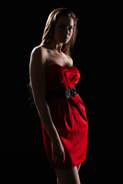 Vrouw in rode jurk op donkere achtergrond — Stockfoto