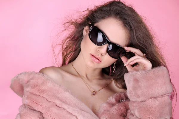 Moda mujer joven con abrigo de piel de invierno posando en respaldo rosa —  Fotos de Stock