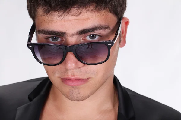 Retrato de un joven guapo con gafas posando sobre una espalda blanca — Foto de Stock