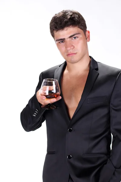Uomo d'affari in tuta nera in possesso di vetro di cognac isolato su w — Foto Stock
