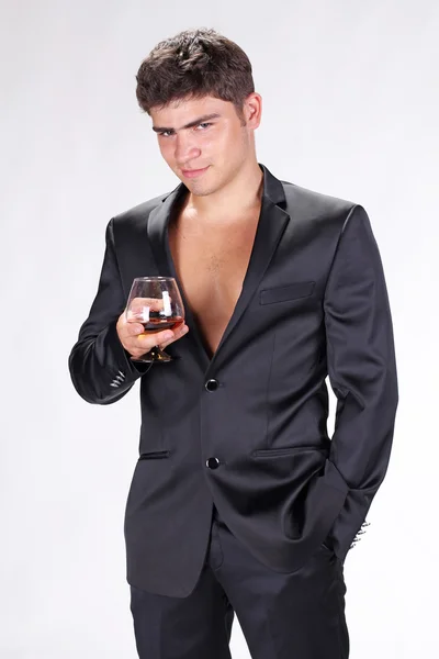Zakenman in zwart pak houden glas cognac geïsoleerd op w — Stockfoto
