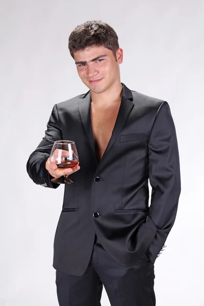 Zakenman in zwart pak houden glas cognac geïsoleerd op w — Stockfoto