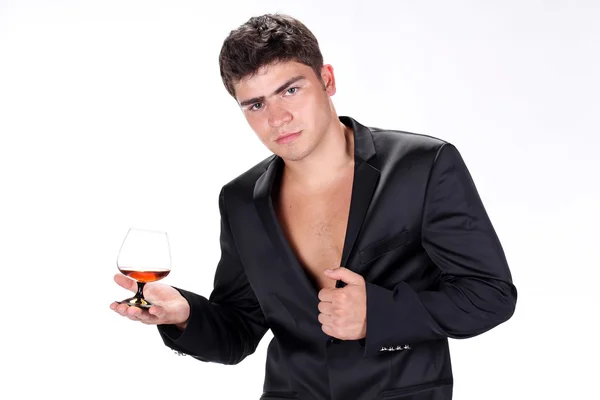 Uomo d'affari in tuta nera in possesso di vetro di cognac isolato su w — Foto Stock