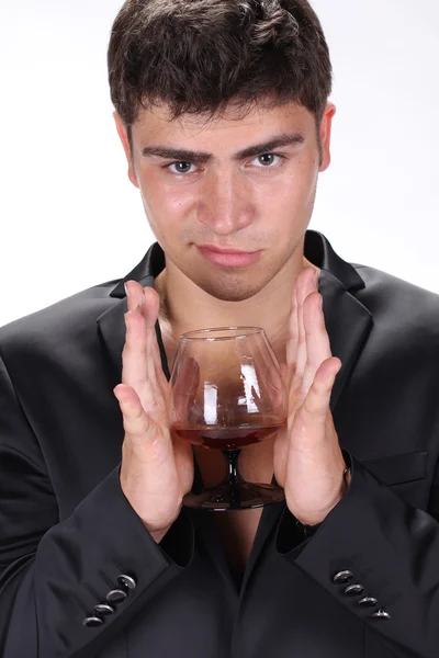 Business man in black suit holding glass of cognac isolated on w — Stock Photo, Image