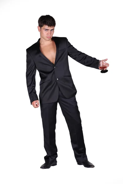 Geschäftsmann im schwarzen Anzug mit einem Glas Cognac isoliert auf dem Kopf — Stockfoto
