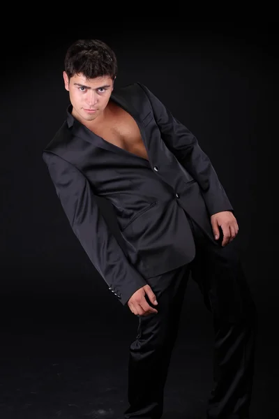 Красивый стильный мужчина в элегантном черном костюме, изолированном на темной стороне — стоковое фото