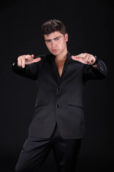 Handsome stylish man in elegant black suit isolated on dark bac — Stock Photo, Image