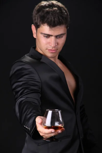 Человек представляет стакан коньяка на темном фоне, бизнес — стоковое фото