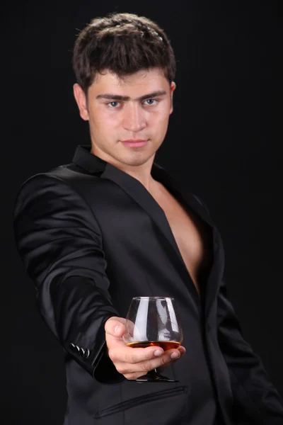 Man present glass of cognac on dark background, business — Stock Photo, Image