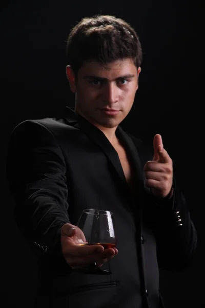 Mann präsentiert Glas Cognac auf dunklem Hintergrund, Geschäft — Stockfoto