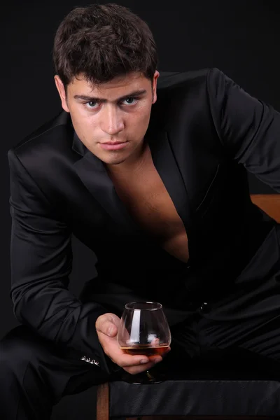 Man present glass of cognac on dark background, business — Stock Photo, Image