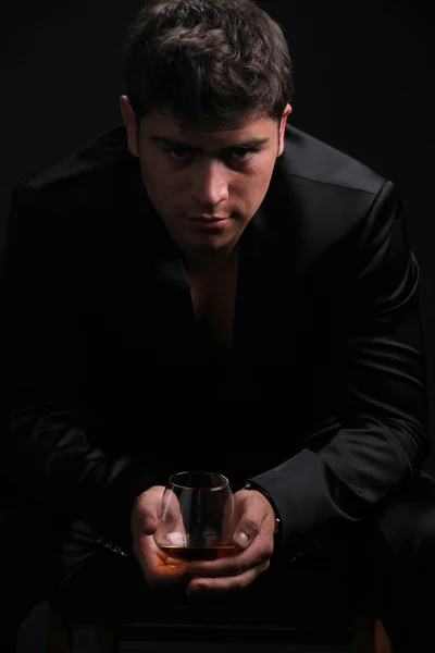 Homem com vidro de conhaque sobre fundo escuro — Fotografia de Stock