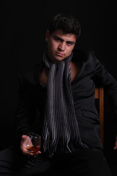 Uomo con vetro di cognac su sfondo scuro — Foto Stock