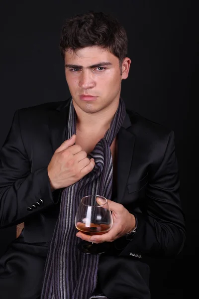 Man with glass of cognac on dark background — Stok Foto