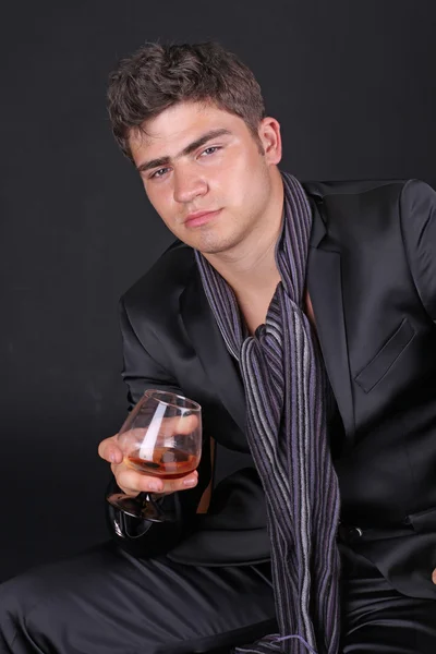 Mann mit Glas Cognac auf dunklem Hintergrund — Stockfoto