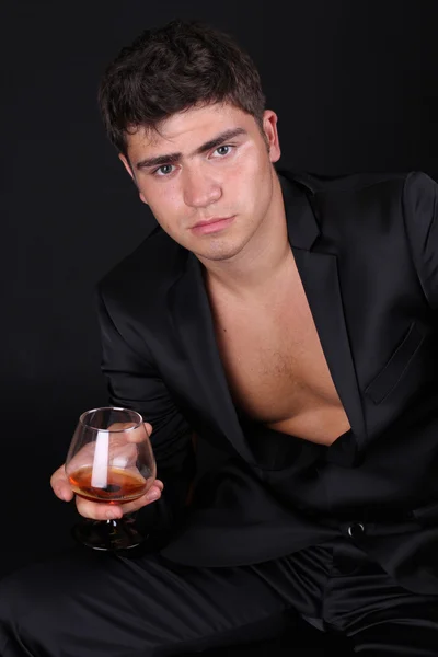 Homme avec verre de cognac sur fond sombre — Photo