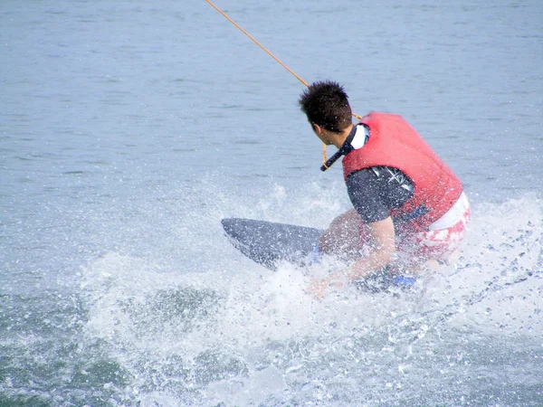 Muž v červených život vesta waterboarding — Stock fotografie