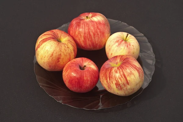 Äpfel auf einem Teller auf schwarzem Hintergrund — Stockfoto