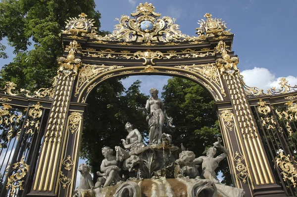 Fontaine encadrée par une porte dorée Image En Vente