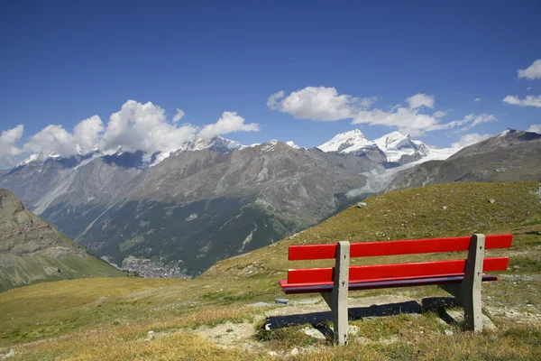 Red bench overlooking the beautiful mountains — Stock Photo, Image