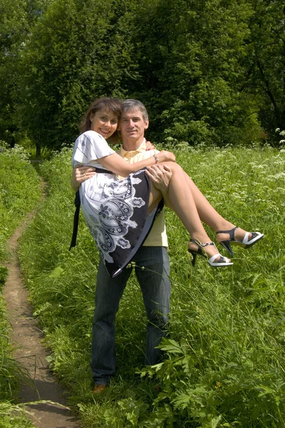 Man carry woman on hands on summer meadow — Stock Photo, Image