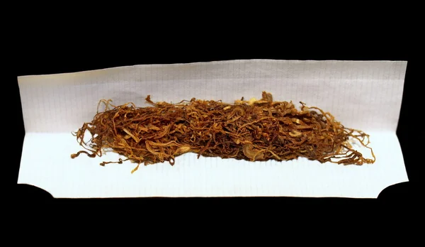 Tabaco e papel para enrolar sobre fundo preto — Fotografia de Stock