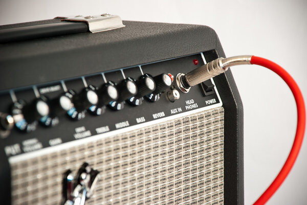 Black guitar amplifier with red cord