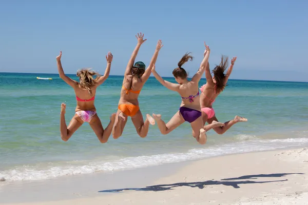 Vier tienermeisjes springen op strand — Stockfoto
