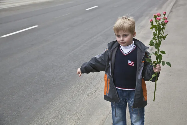 A boy with flowers stops the car — 图库照片