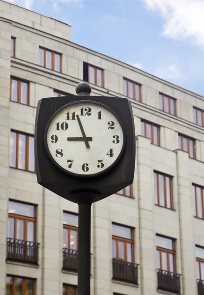 Уличные часы перед зданием — стоковое фото