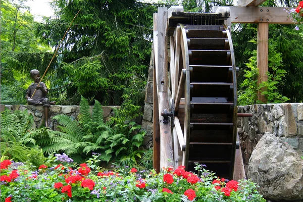 Ruota idraulica in un giardino fiorito — Foto Stock