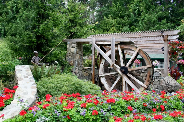 Květinová zahrada a waterwheel — Stock fotografie