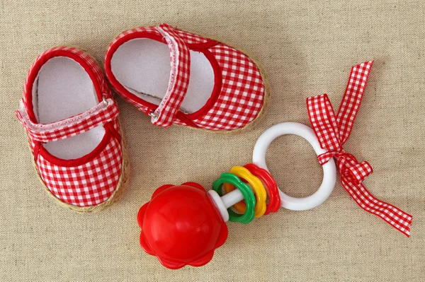 Baby rattle and red shoes — Stock Photo, Image
