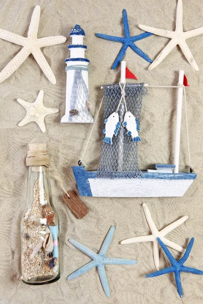 Faro, nave, bottiglia e stelle del mare sulla sabbia — Foto Stock