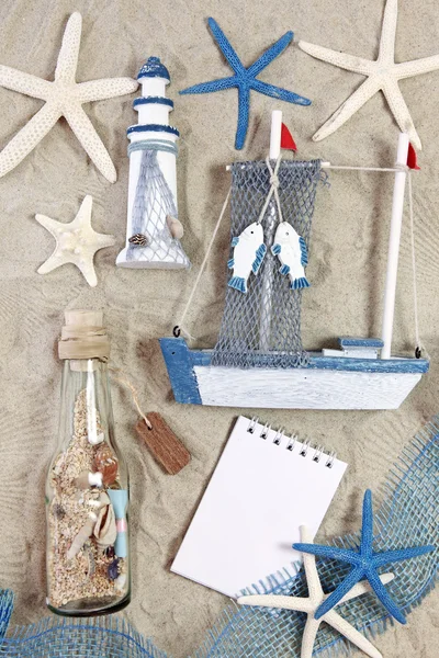 Маяк, корабль, бутылка и морские звезды на песке — стоковое фото