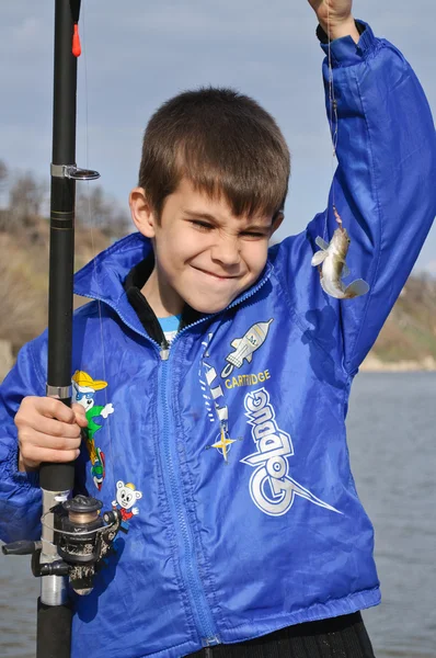 A boy with a fishing pole caught small fish — Stock Photo, Image