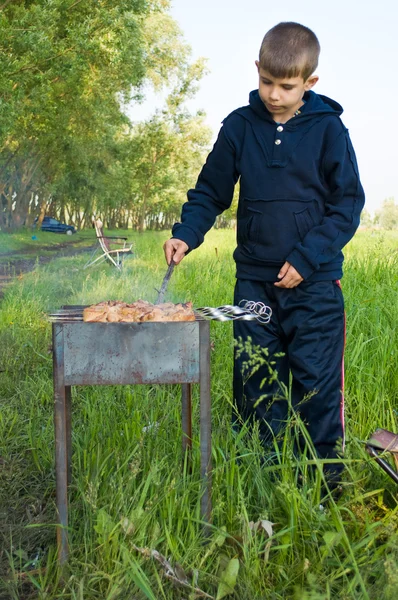 その少年は肉をグリルする準備をしてください。 — ストック写真