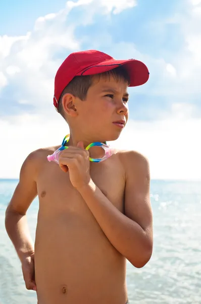 A boy in a baseball cap, standingagainst the backdrop of the sea — Stock Photo, Image