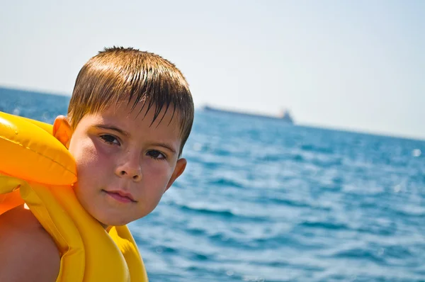 Boy in life jacket, standing in the background of the sea — Stock Photo, Image