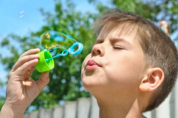 A little boy blows bubbles — Stock Photo, Image