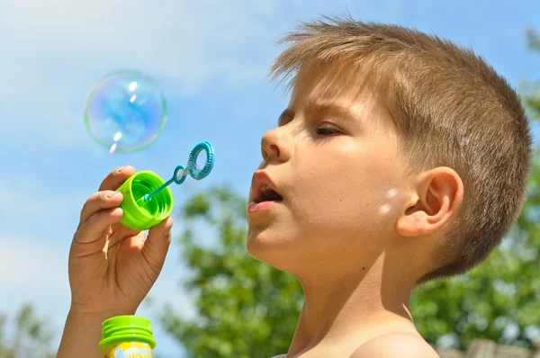 Маленький хлопчик дме бульбашки — стокове фото