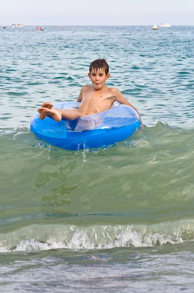 Мальчик с надувными колесами по волнам — стоковое фото